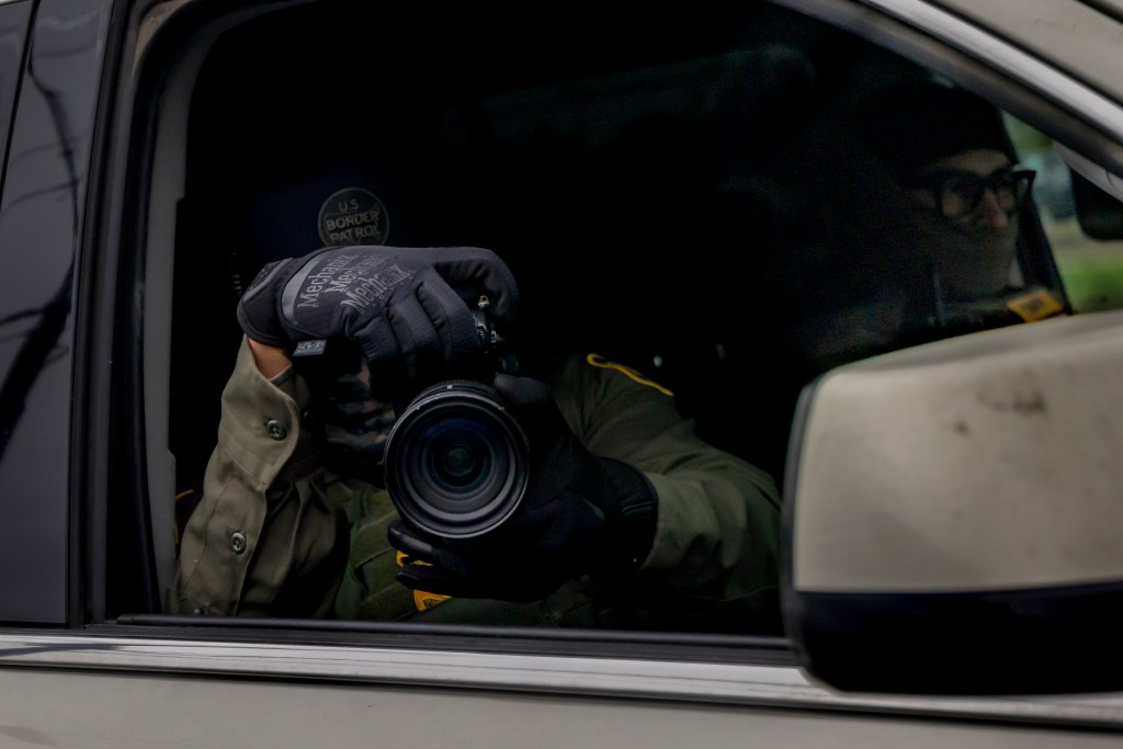 A U.S. Border Patrol Chief Patrol Agent films community members and the press during immigration enforcement operations on December ​5, 2025, in New Orleans, Louisiana. Federal agents participating in 'Catahoula Crunch,' patrol through ​New Orleans neighborhoods and surrounding suburbs searching for undocumented immigrants.